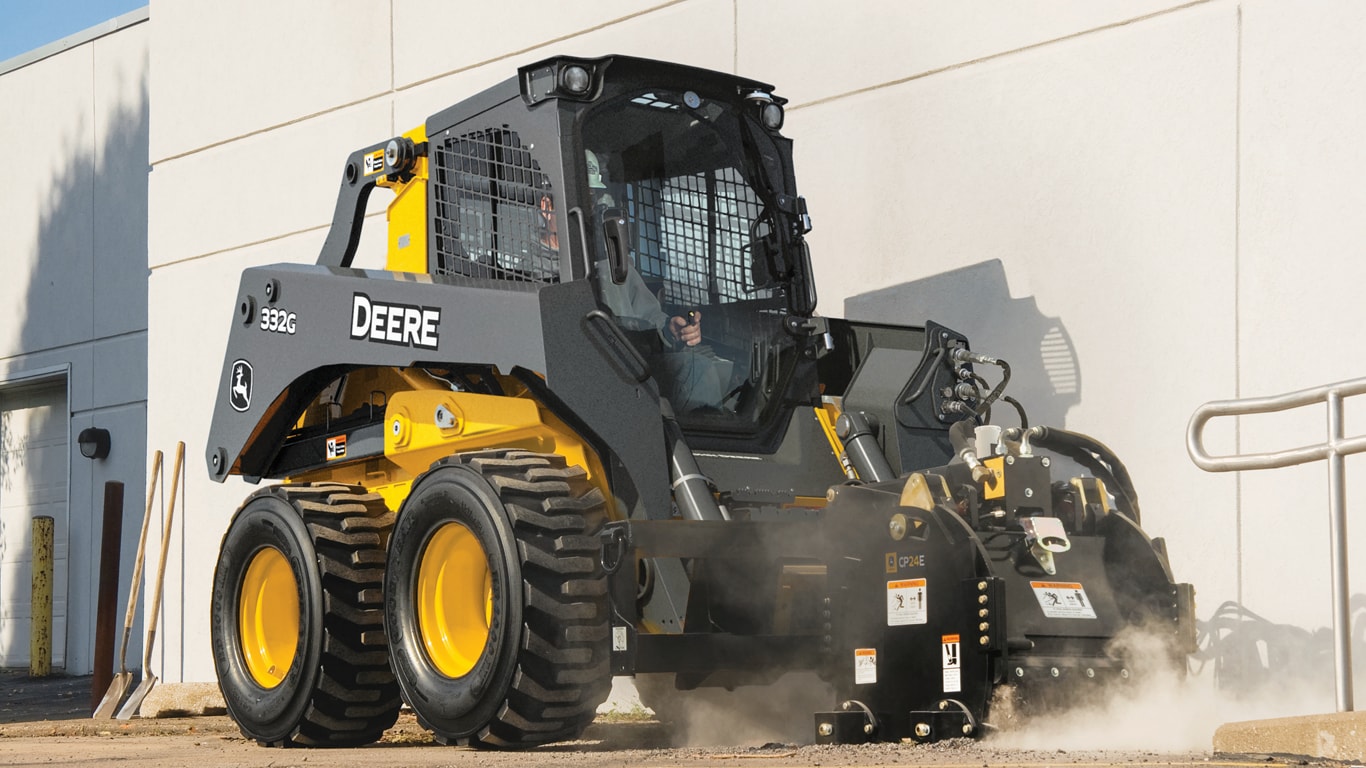 Chargeuse à direction différentielle John Deere équipée d'un accessoire pour plaque de compactage