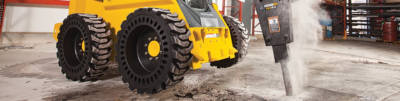 Hydraulic Hammer attachment on a 318E Skid Steer busting up the concrete floor of a building.