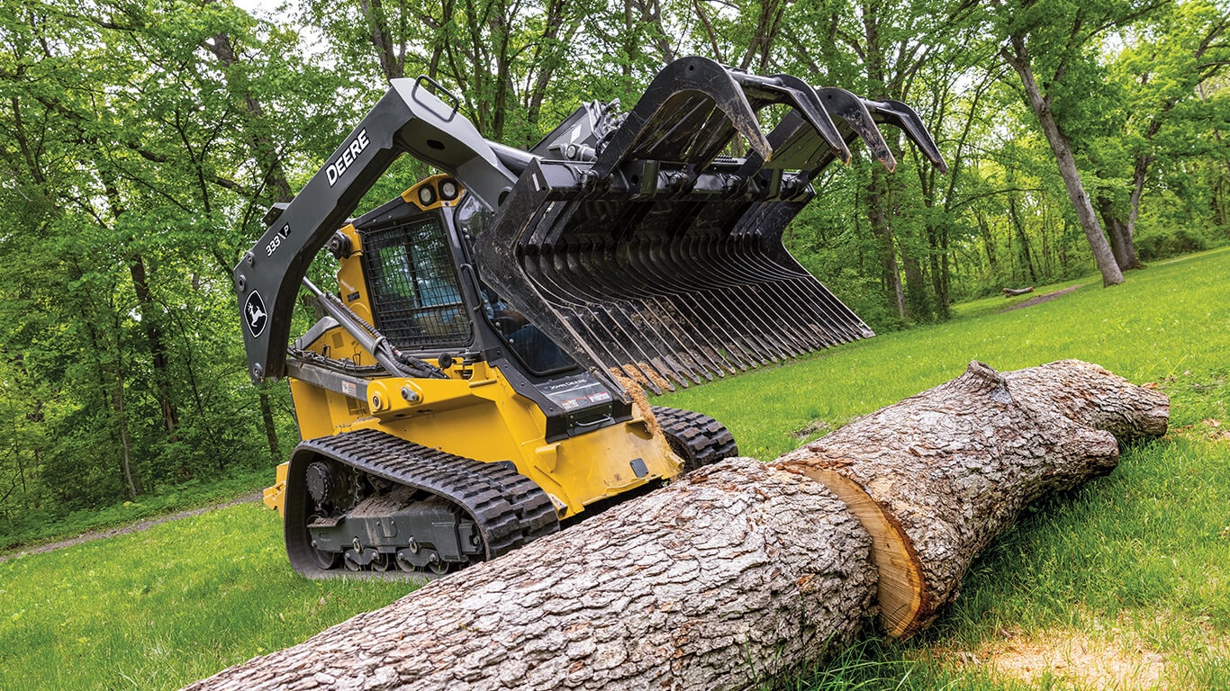 333 P-Tier compact track loader using John Deere grapple attachment to move large log.