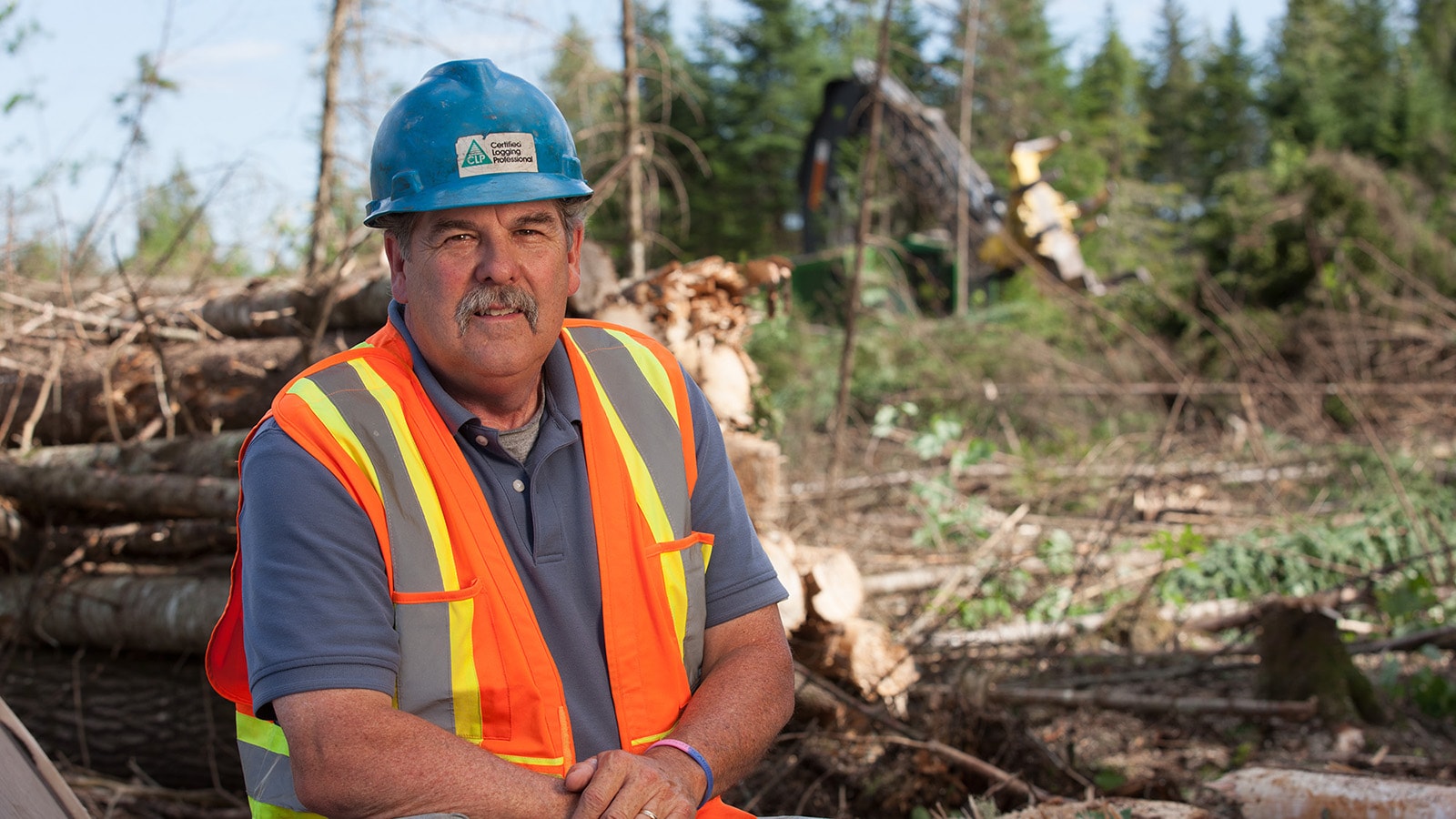 Dan Melcher poses with his logging operation in the background