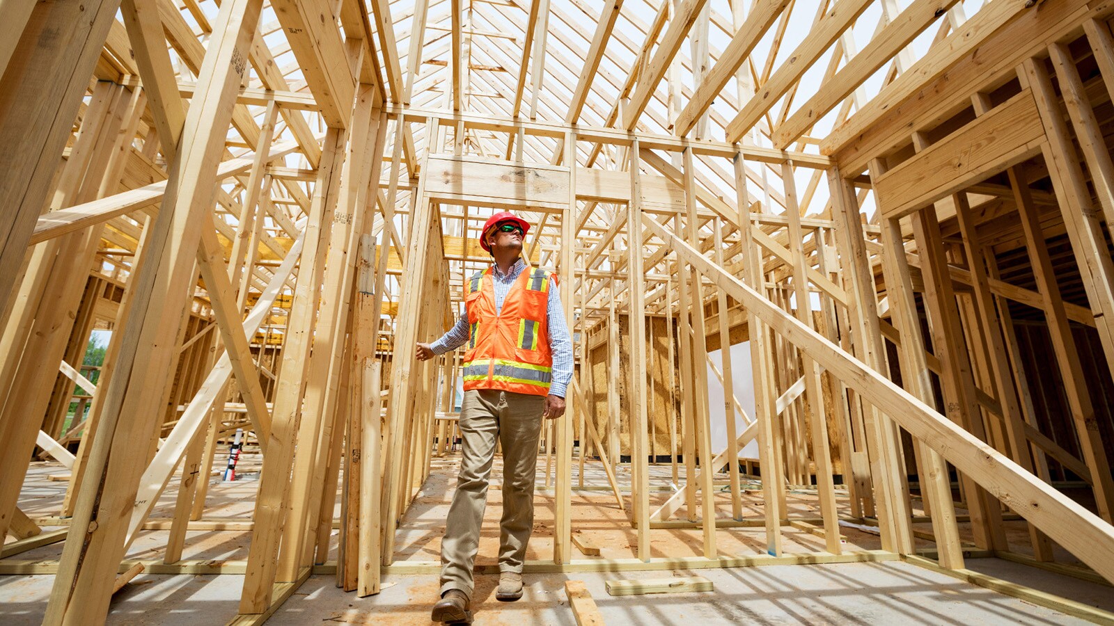 On a bright day with blue skies, Matt Lovell walks through the frame of a home his company is working on.