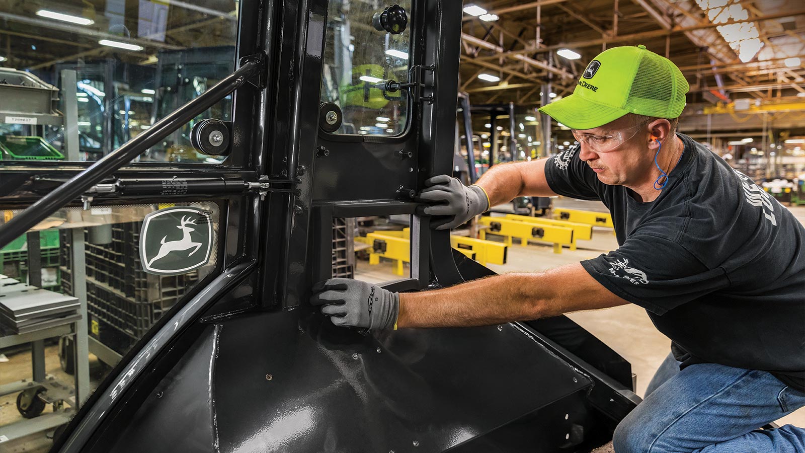 A factory worker works on a Deere wheel loader