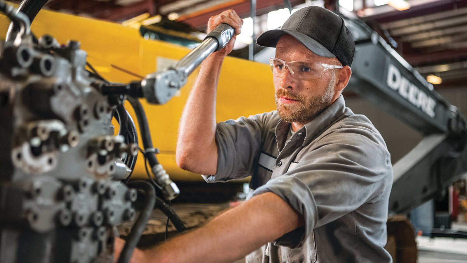 A factory worker works on a piece of construction equipment