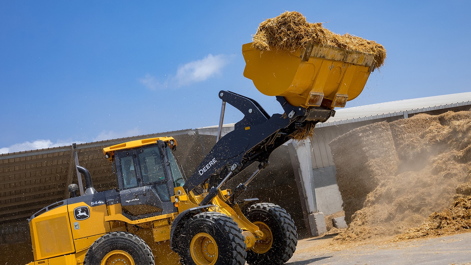 544L Wheel Loader transfers loose straw from a large pile