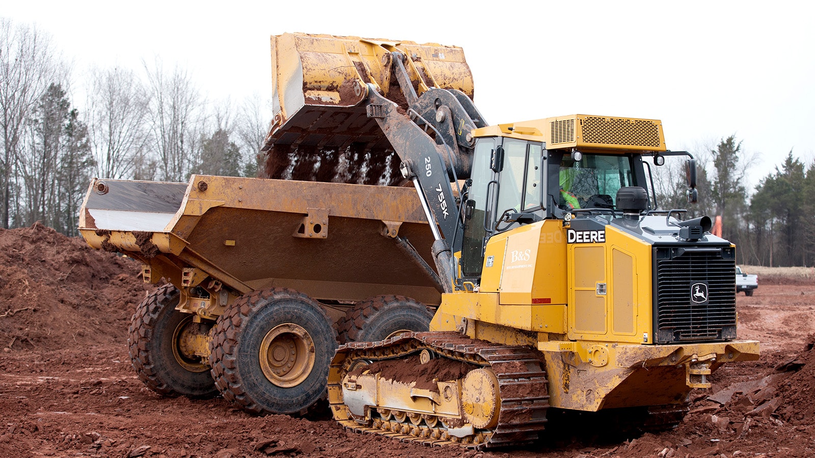 755K Crawler Loader loads a dump truck with dirt