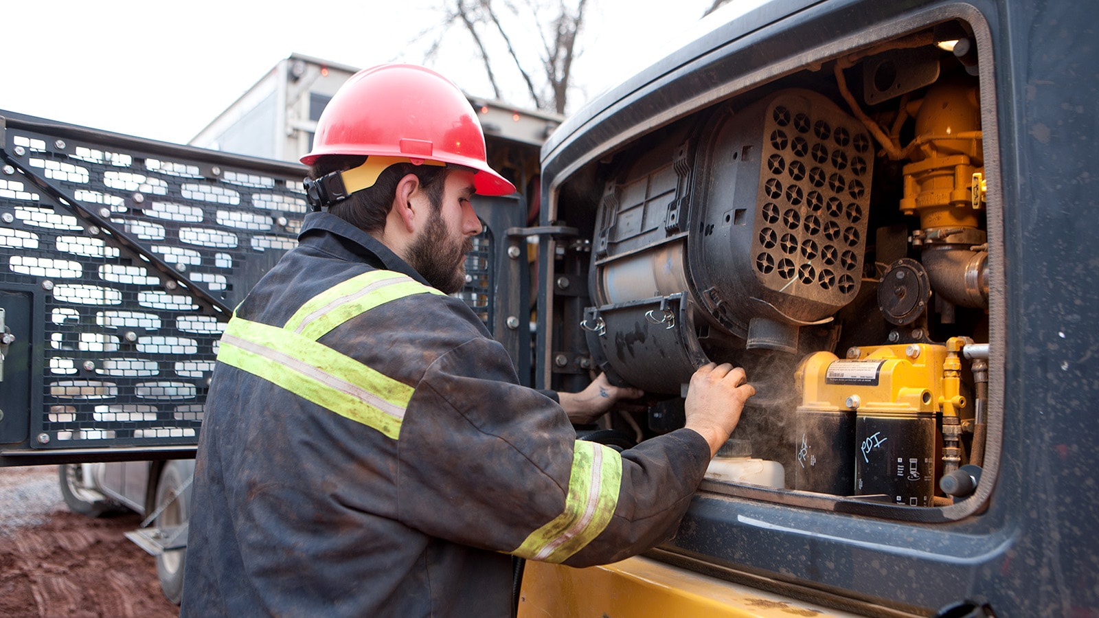 A person works inside the front service panel of an articulated dump truck