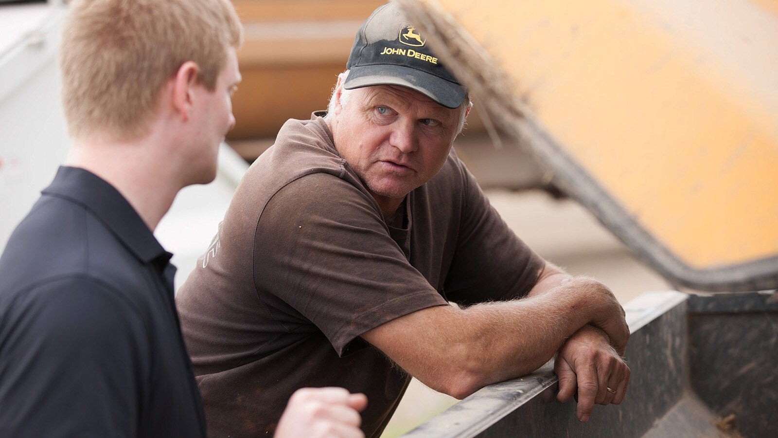 Roy Grewe and Brock Grewe stand over the 324K wheel loader talking