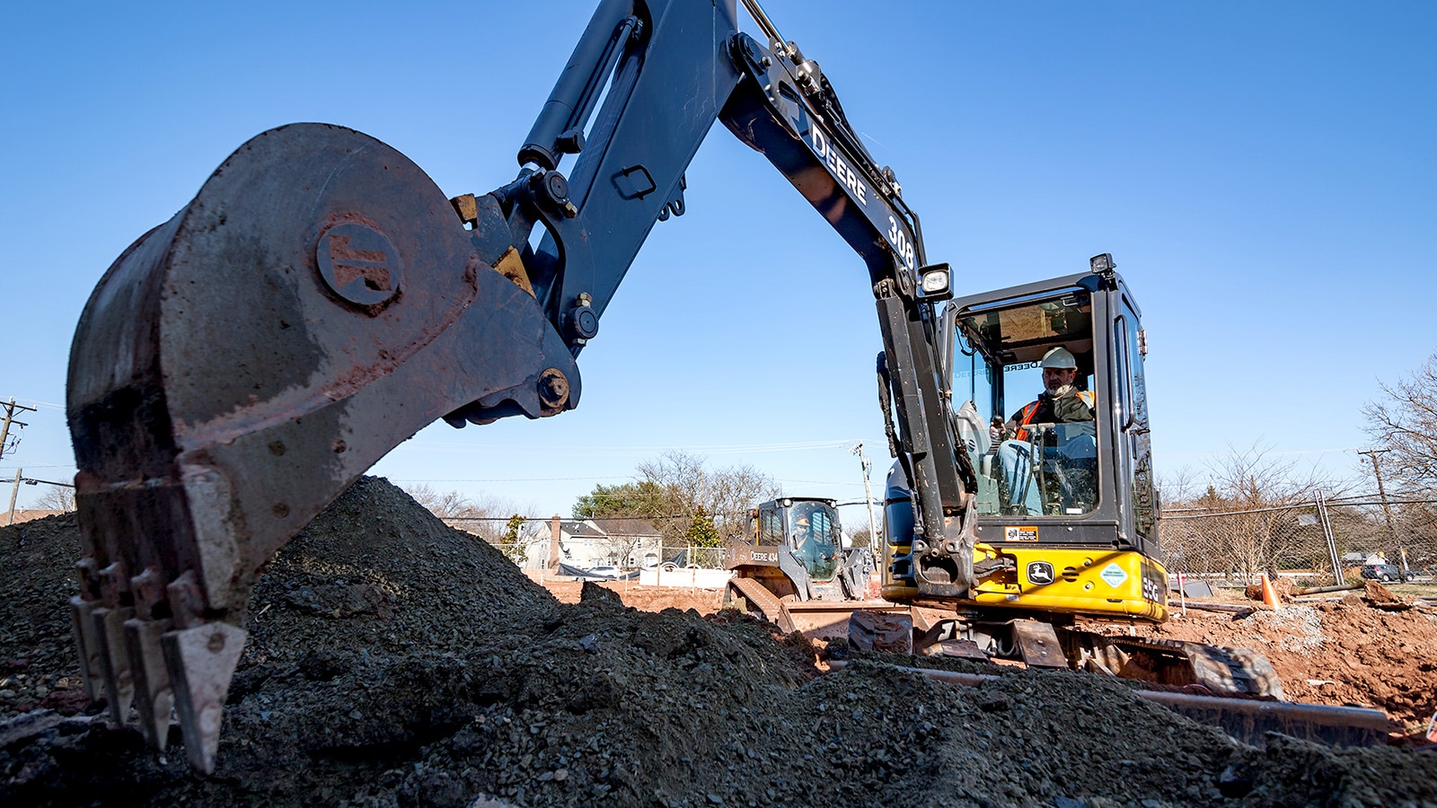 Close up view of 35G Compact Excavator’s bucket just about to take a scoop of rich, black dirt from a pile.