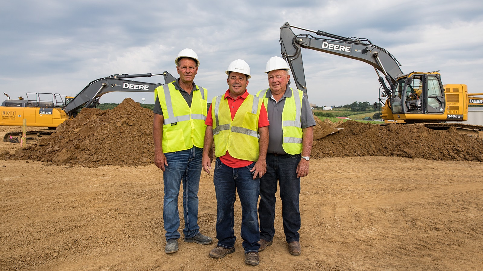 Pat, Matt and Rod Horsfield of Horsfield Companies stand in front of two of their John Deere excavators