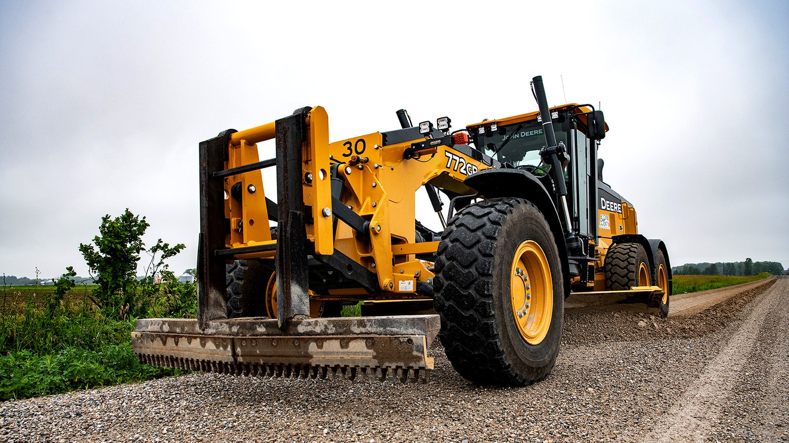 772GP Motor Grader spreads gravel on a road