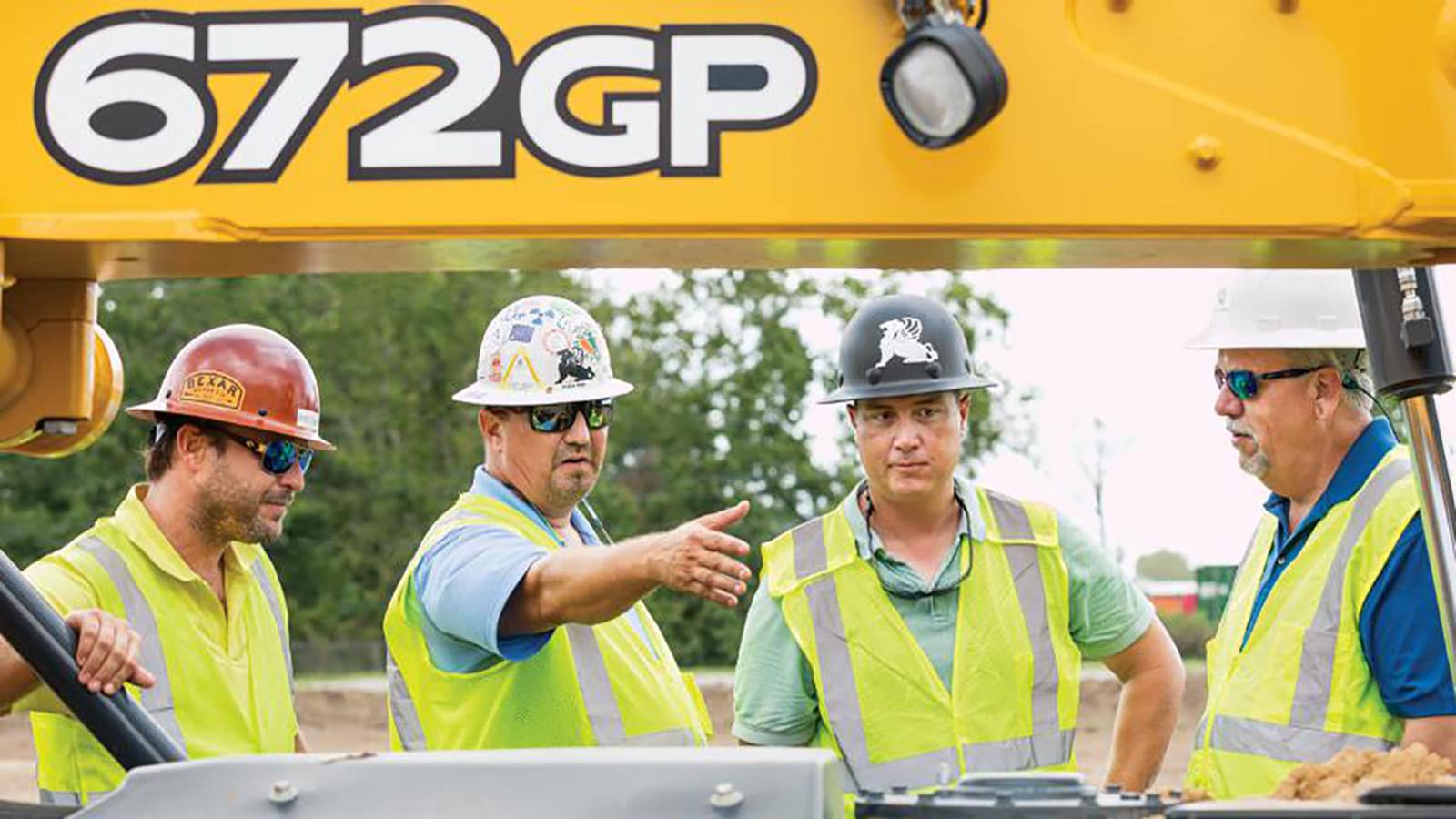 Brent Bazemore, Richie West, and Jerald Grantham, Griffin Contracting Inc., meet with Matt Smallwood, Flint Equipment Company, wearing hard hats and safety vests meet on a jobsite next to a 672GP.