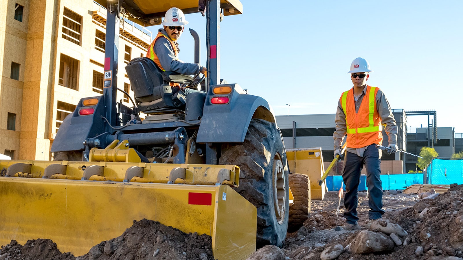 A 210lep tractor loader working in the tight spaces of an apartment constuction site.