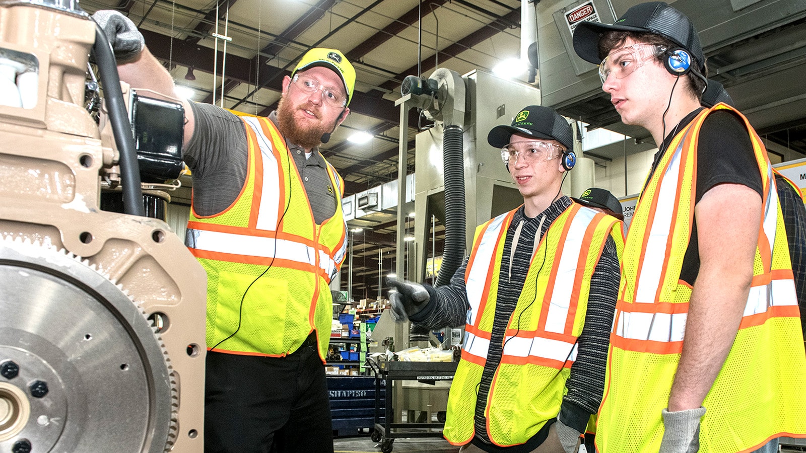 Students listen to their tour guide pointing at a remanufactured component in the Springfield facility