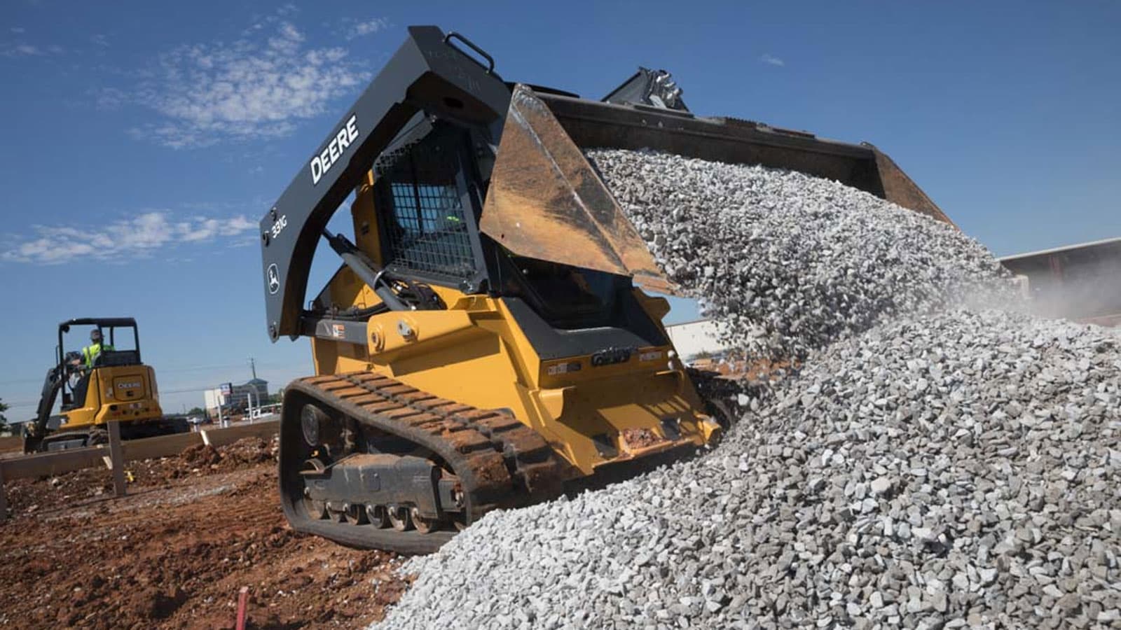 A 331G scoops gravel in the foreground on a work site in Huntsville, Alabama while a 35G works in the background.