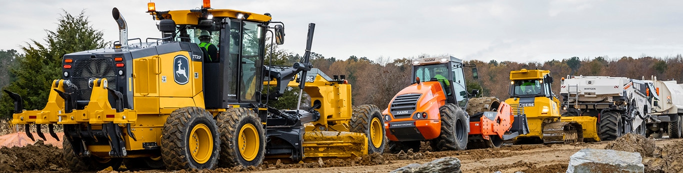 Une niveleuse automotrice John Deere au travail sur un chantier de construction routière