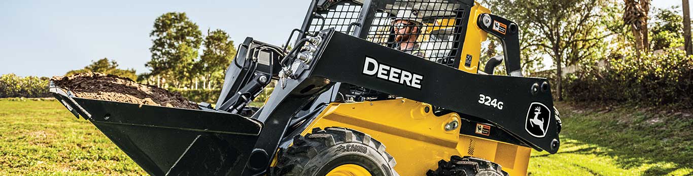 Skid Steer against a backdrop of rolling green fields.