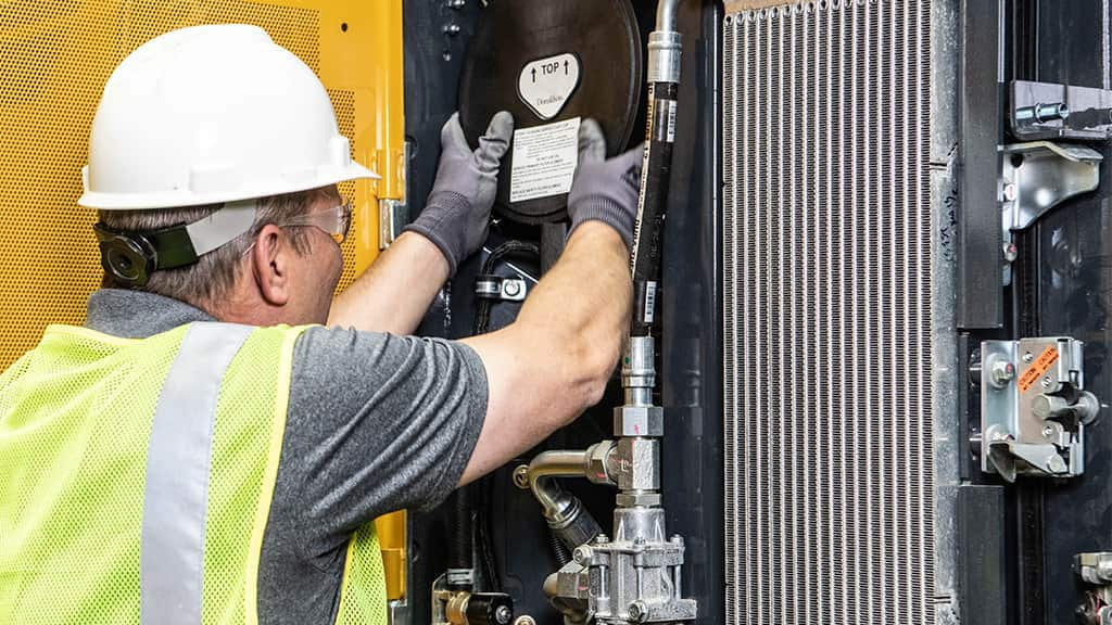 Distributeur de moteurs John Deere travaillant sur un moteur industriel à l’intérieur d’un d’équipement