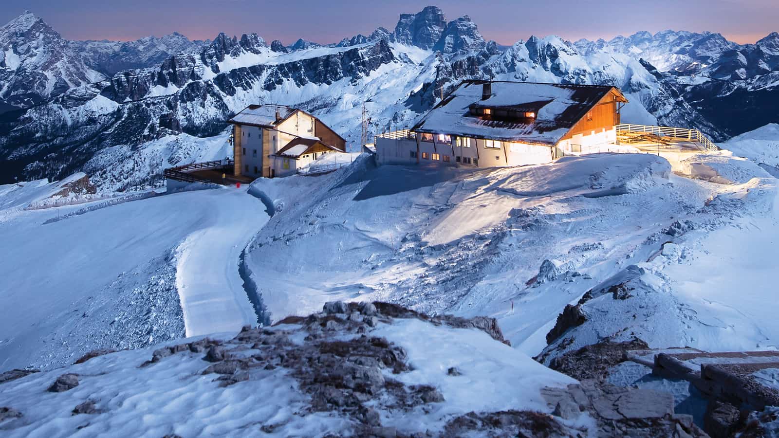 Cabins on a high mountain peak with bright lights turned on.