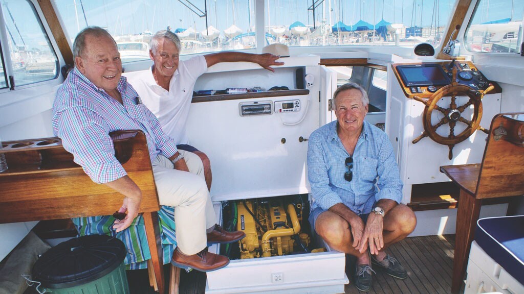 Trois copropriétaires assis devant un moteur marin John Deere sur leur bateau, l'Avril