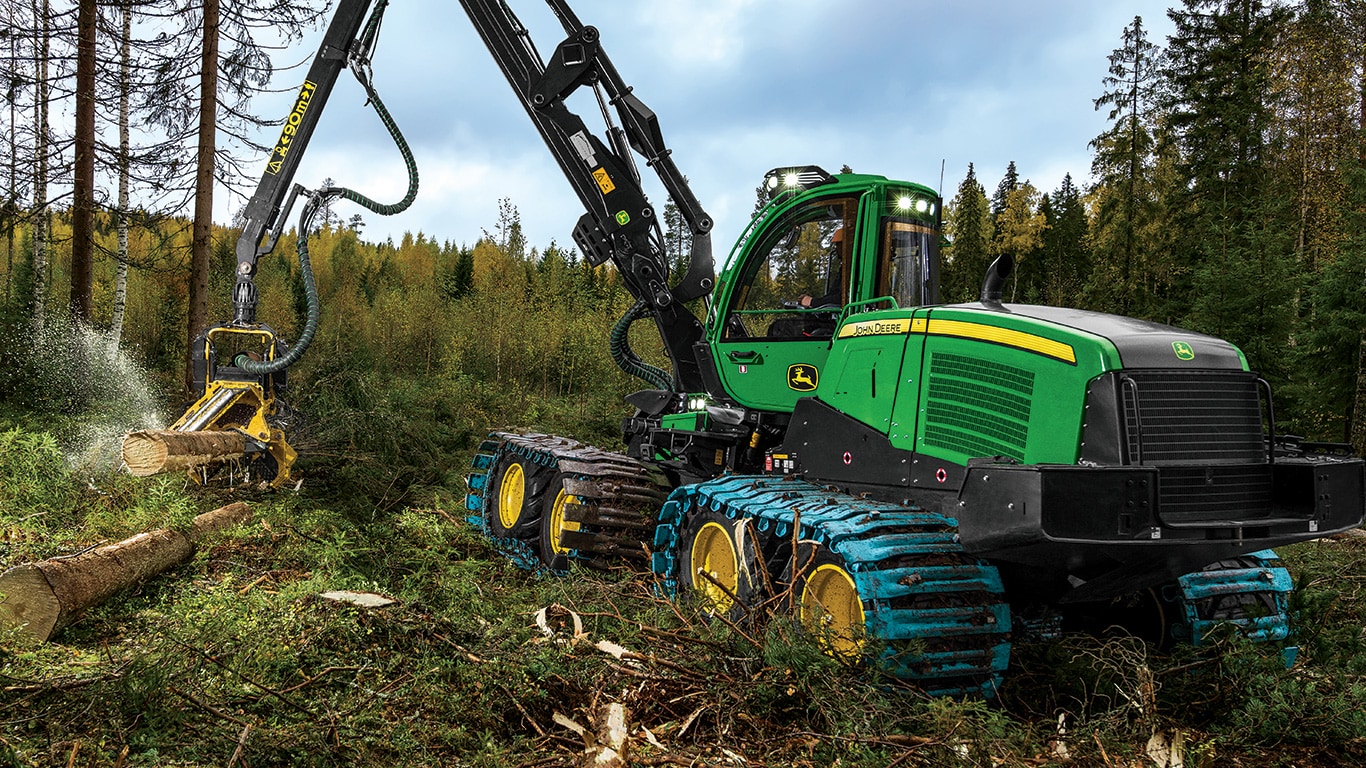 Une abatteuse-façonneuse à roues 1170G John Deere équipée d’une tête d’abattage H414 traite des rondins abattus.