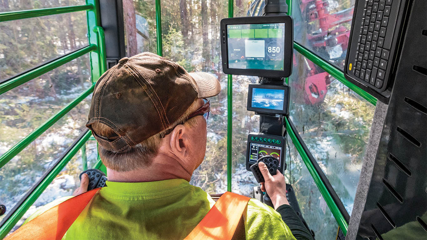 An in-cab view shows an operator looking at multiple screens, highlighting the technology options on John Deere forestry equipment.