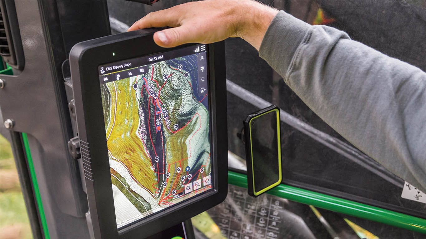 An operator's hand rests on top of a screen showing a Timbermatic map.