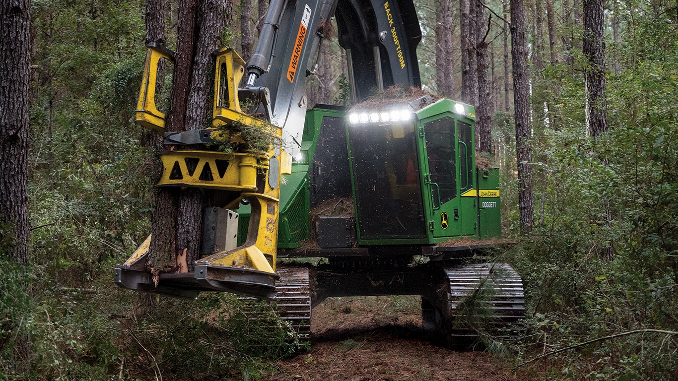 Une abatteuse-groupeuse chenillée 853M John Deere avec tête d’abattage FR50 en train d’abattre un arbre dans la forêt.