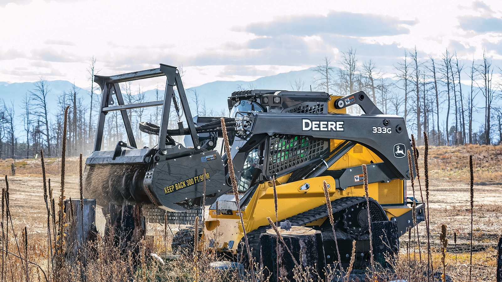 333G Compact Track Loader with MH60D Mulching Head attachment grinds down a stump in a cleared area affected by wildfires