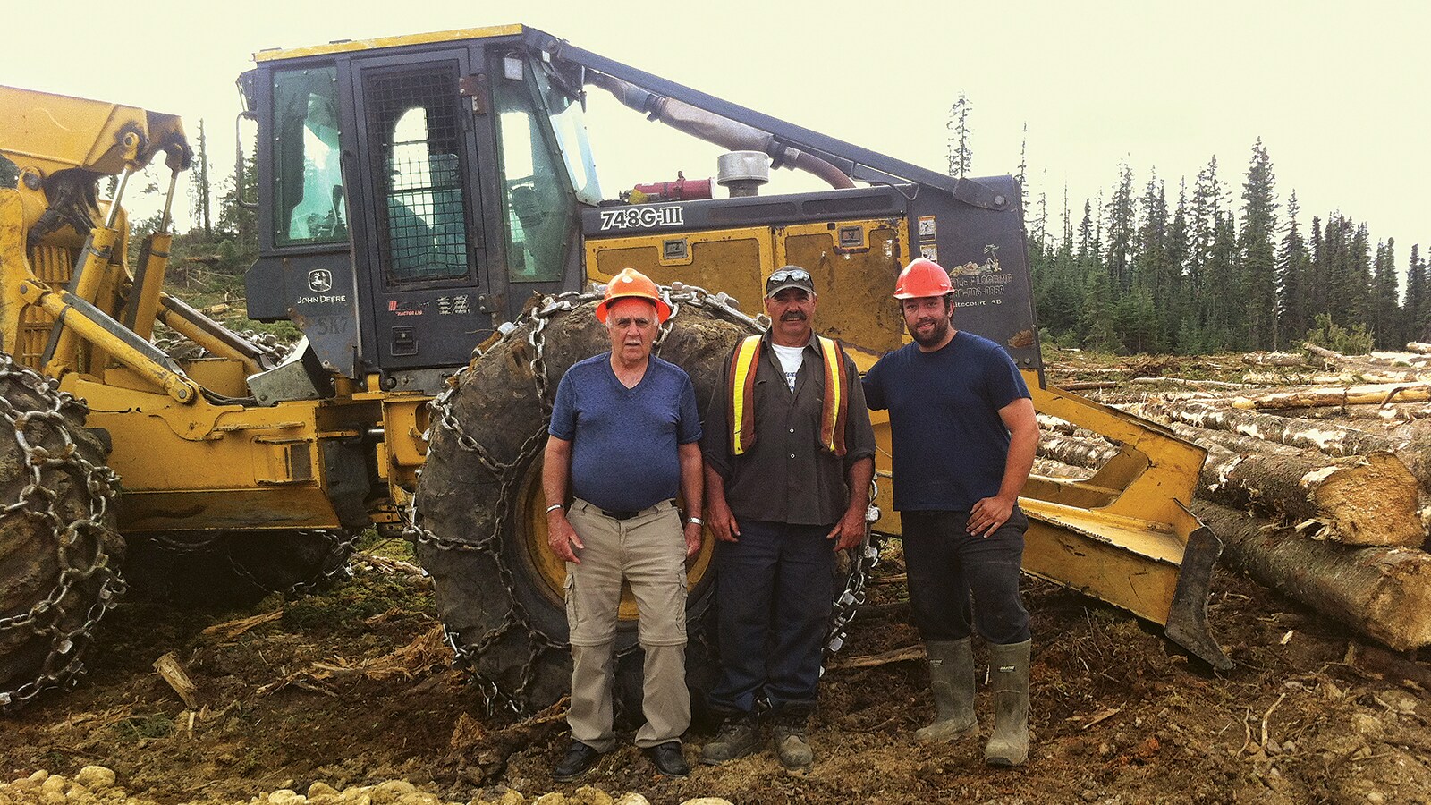  Three men from the Freake family stand in front of their 548G-III Skidder