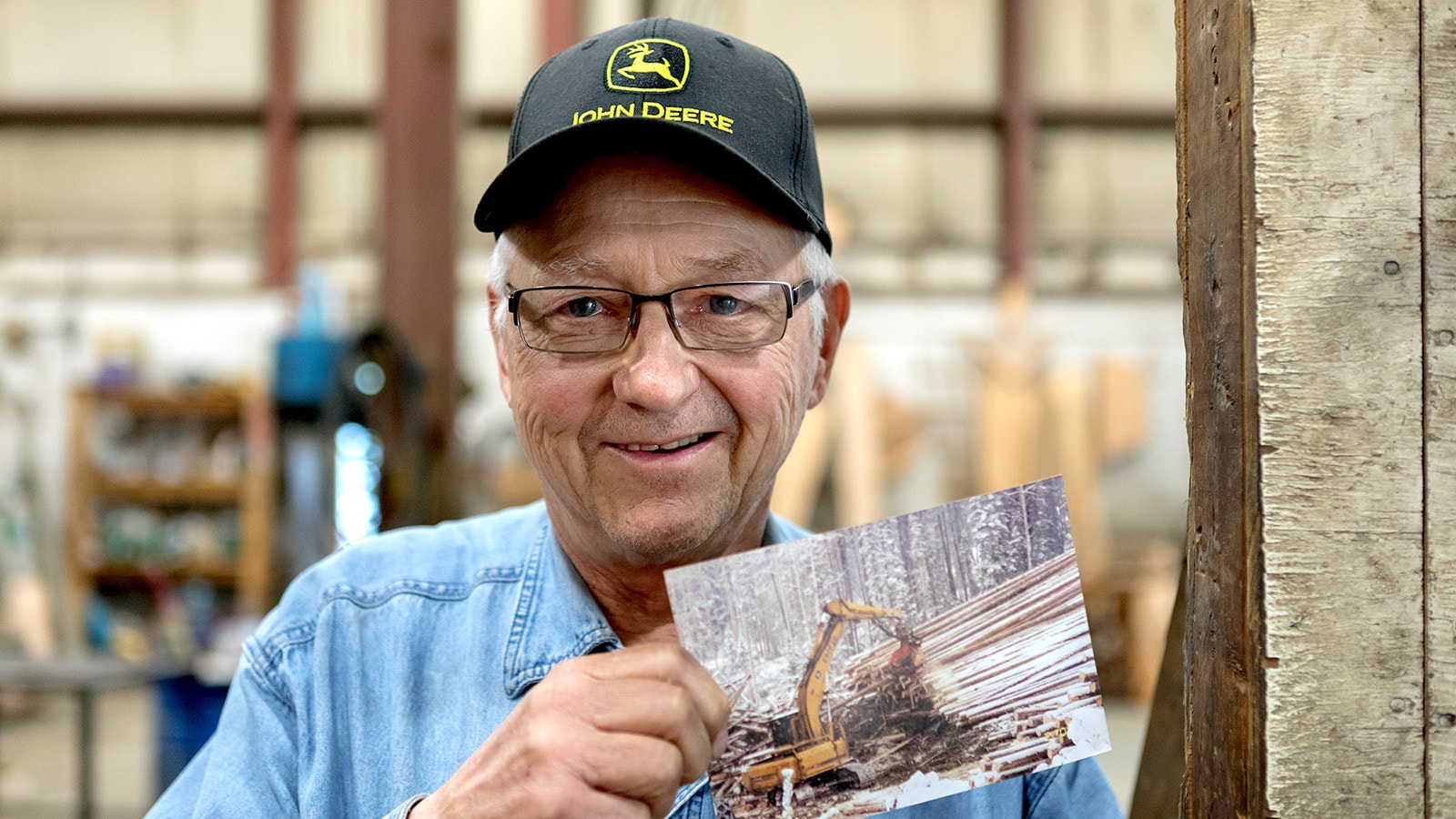 Daniel Mattey holds a photo of his Deere 690E LC