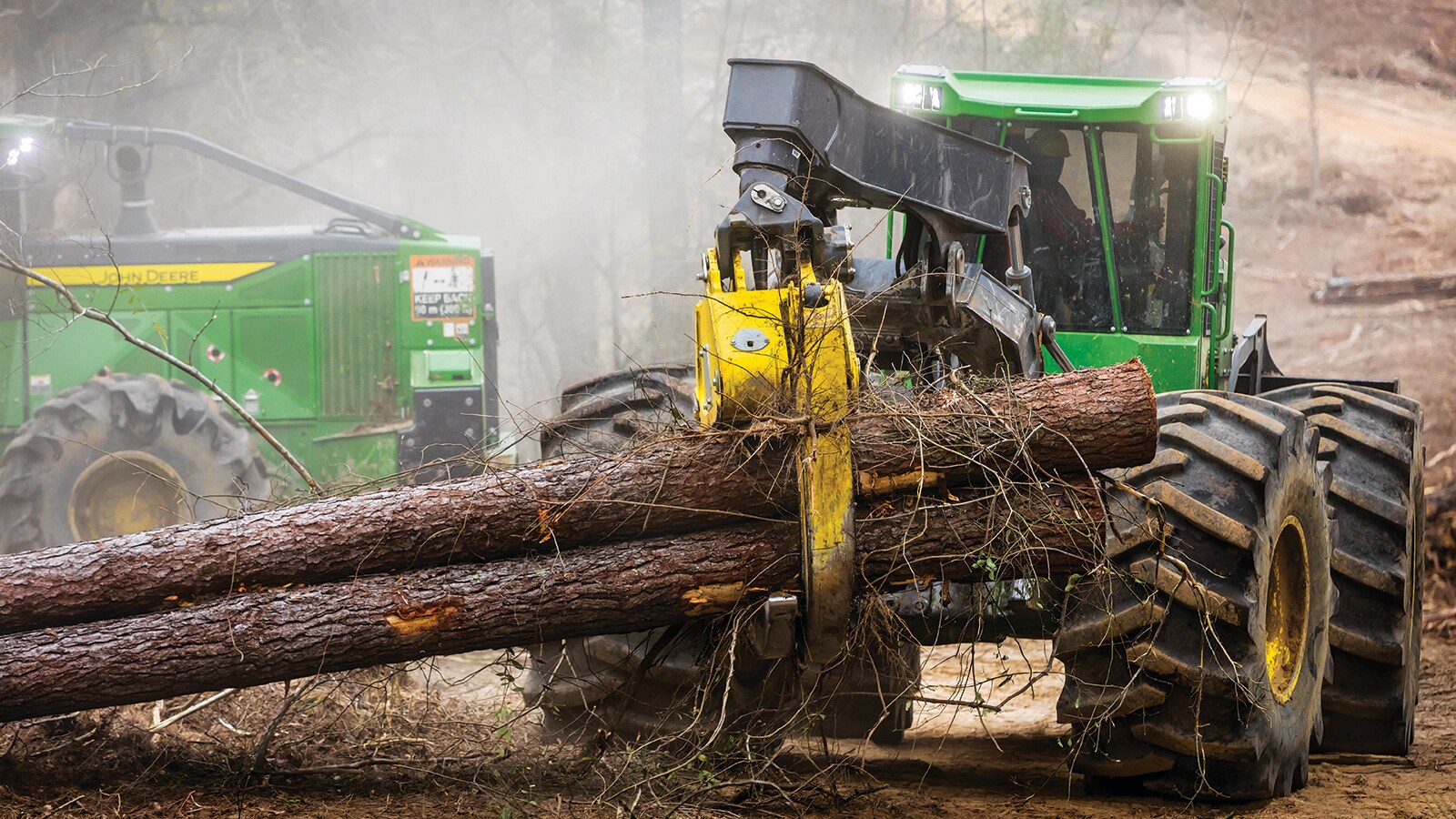 Skidder hauling a load of logs through a cloud of dust