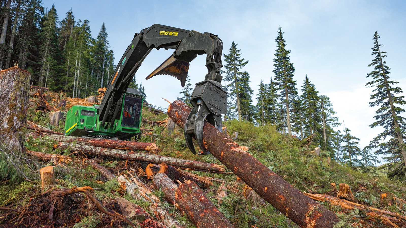 959ML Shovel Logger hauls a felled log up the side of a mountain