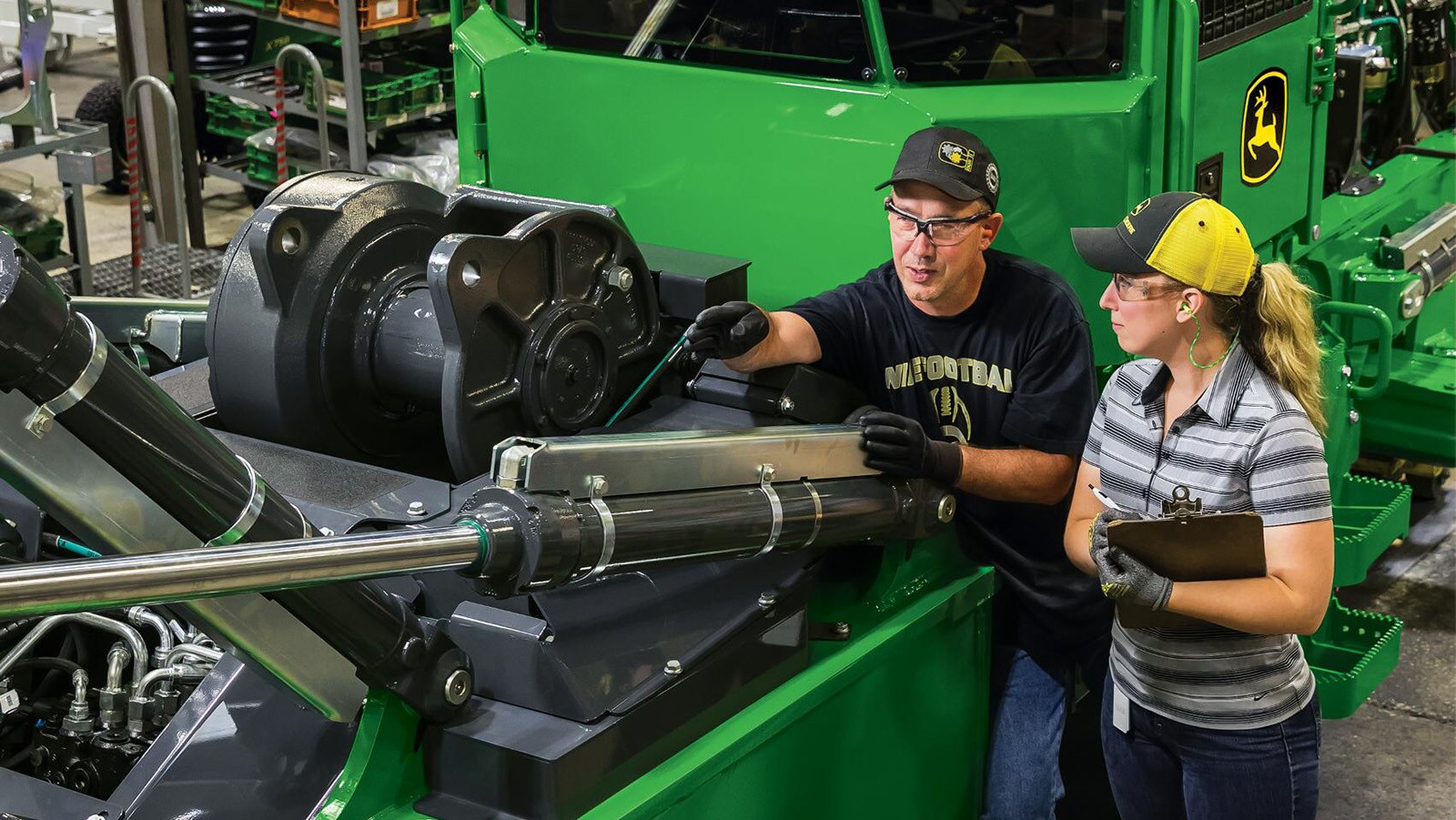 two factory workers talk while looking at a 748L-II Skidder