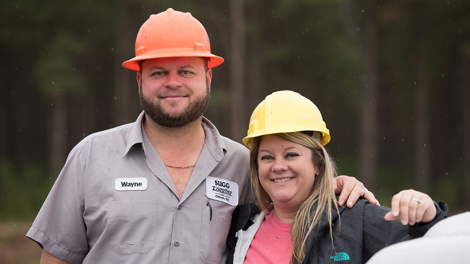 Wayne and Tina Sugg stand at their jobsite and smile for a photo