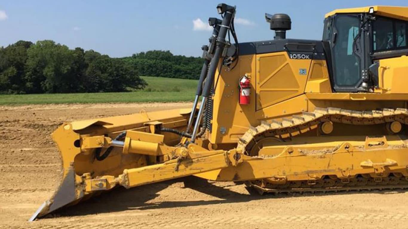 Close-up image of a 1050K Dozer with mechanical angle blade in the dirt