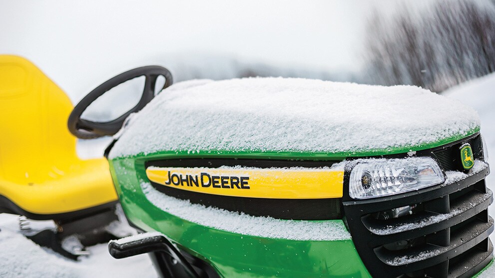 Close up image of John Deere lawn tractor covered in a light layer of snow
