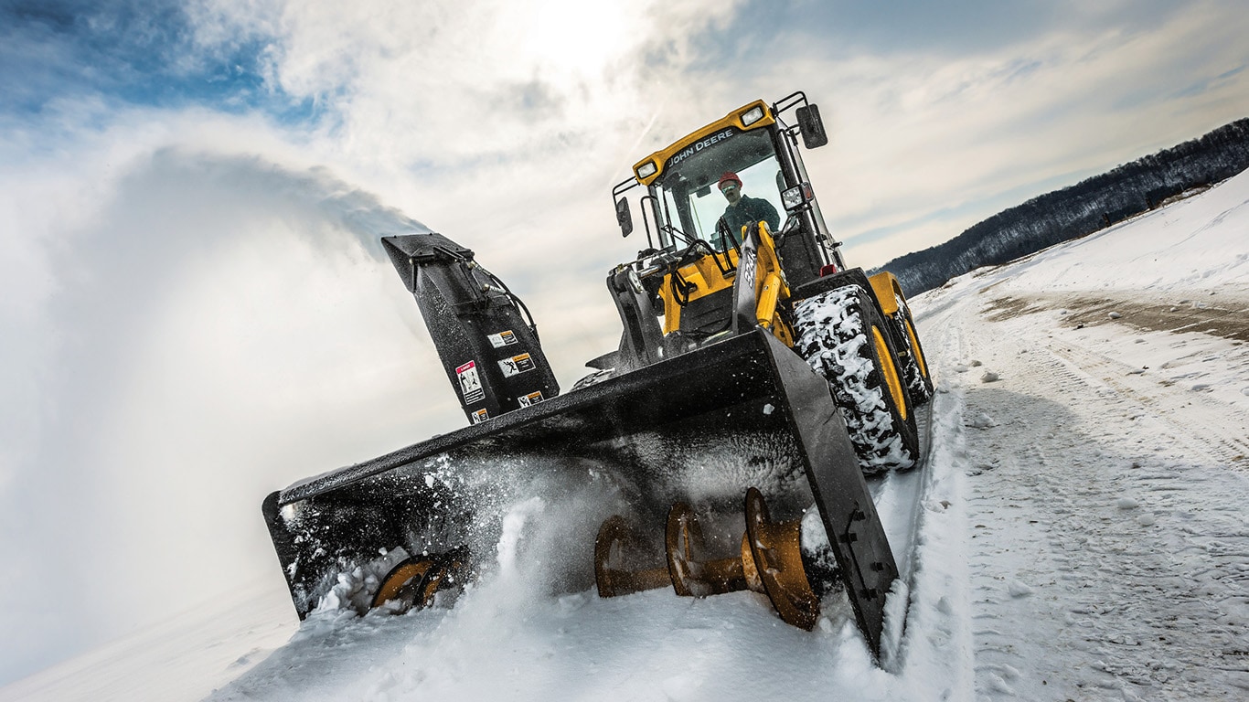 A John Deere Compact wheel loader with snowblower attachment working