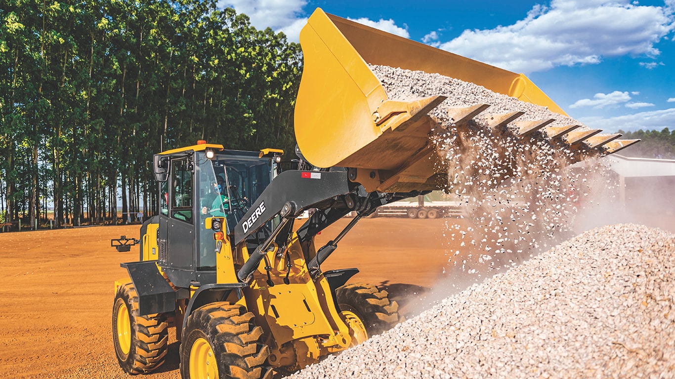 Action shot of the 444 G-Tier Wheel Loader dumping rocks on the job site