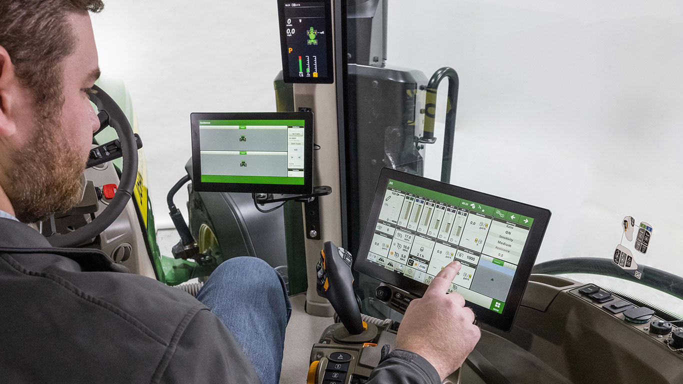 Man inside tractor touching digital screen.