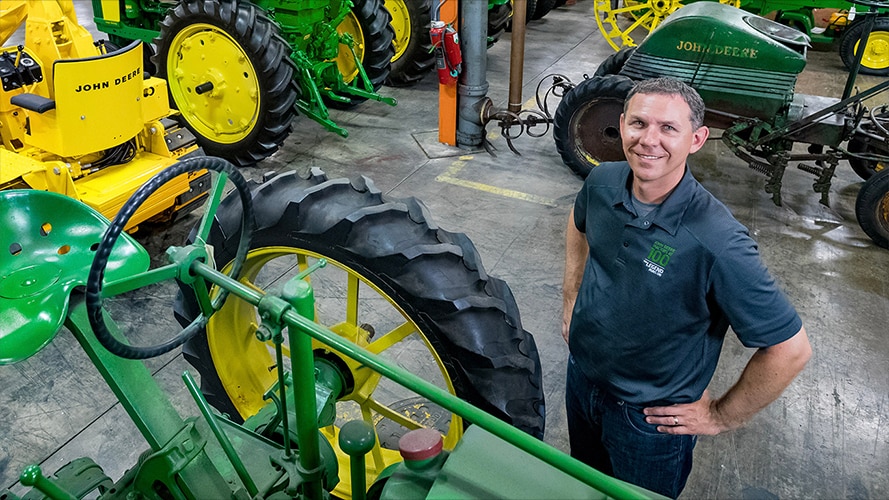 Neil Dahlstrom standing next to vintage John Deere tractors