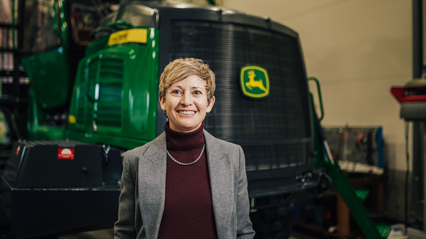 Mary&nbsp;Pat&nbsp;Tubb, Vice President, Worldwide Forestry at Deere&nbsp;&amp;&nbsp;Company, smiling in front of John&nbsp;Deere equipment.