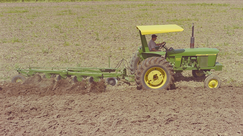 John Deere 4020 tractor from 1964 tilling a field in the Midwest of America