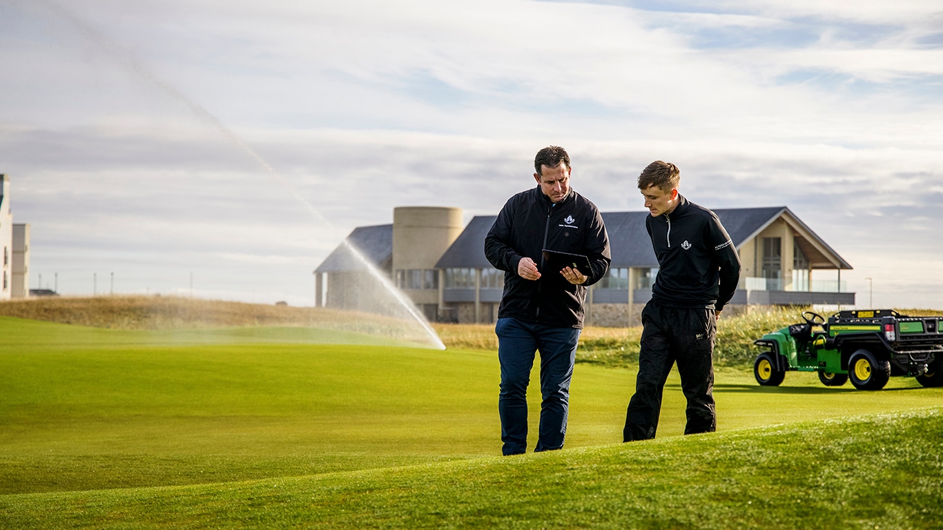 Two men looking at a tablet on a golf course