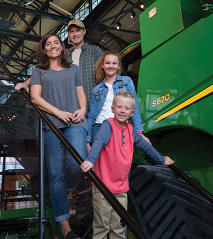 Une famille de quatre pose devant une moissonneuse-batteuse au John Deere Pavilion