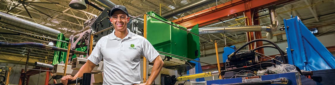 John Deere employee stands in front of factory equipment