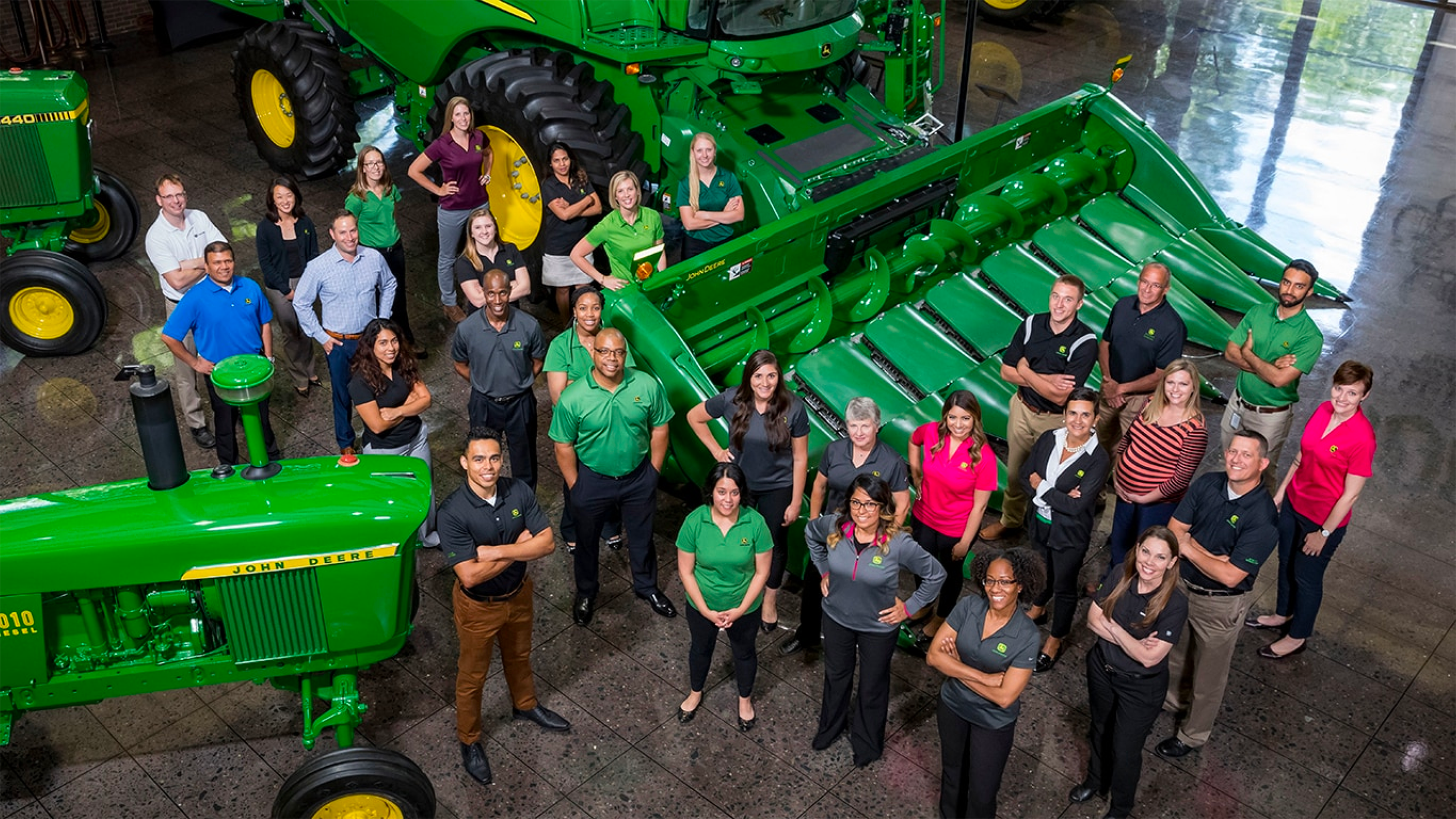 A group of people standing amongst Deere equipment