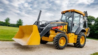 John Deere 310 X-Tier E-Power backhoe driving on gravel