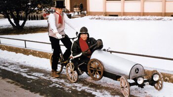 Two teens riding a vehicle they made for a parade.