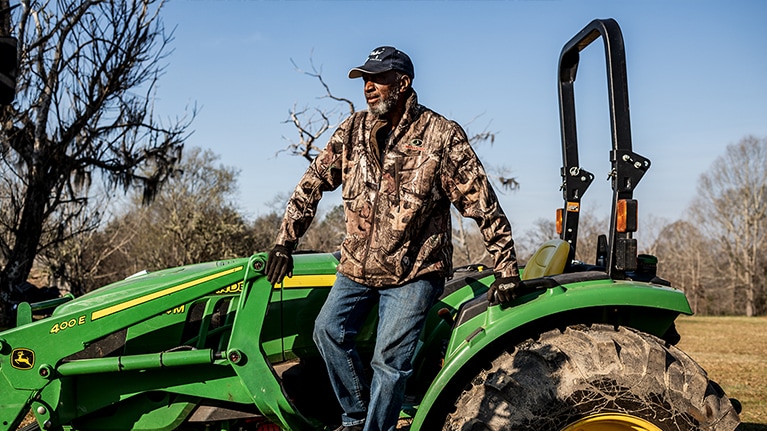 A farmer standing next to his John Deere tractor