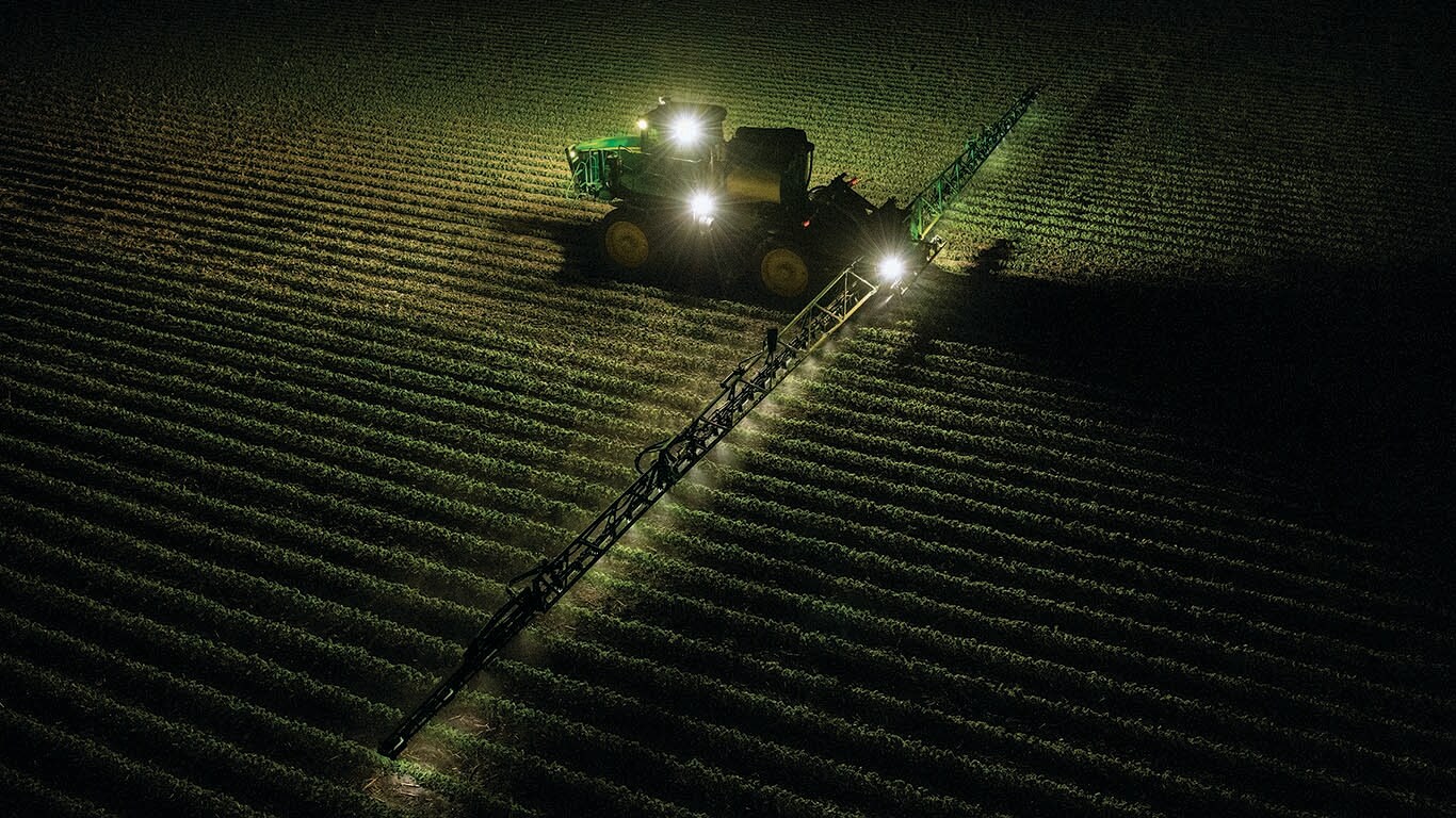 Un pulvérisateur 412R au travail dans un champ en soirée
